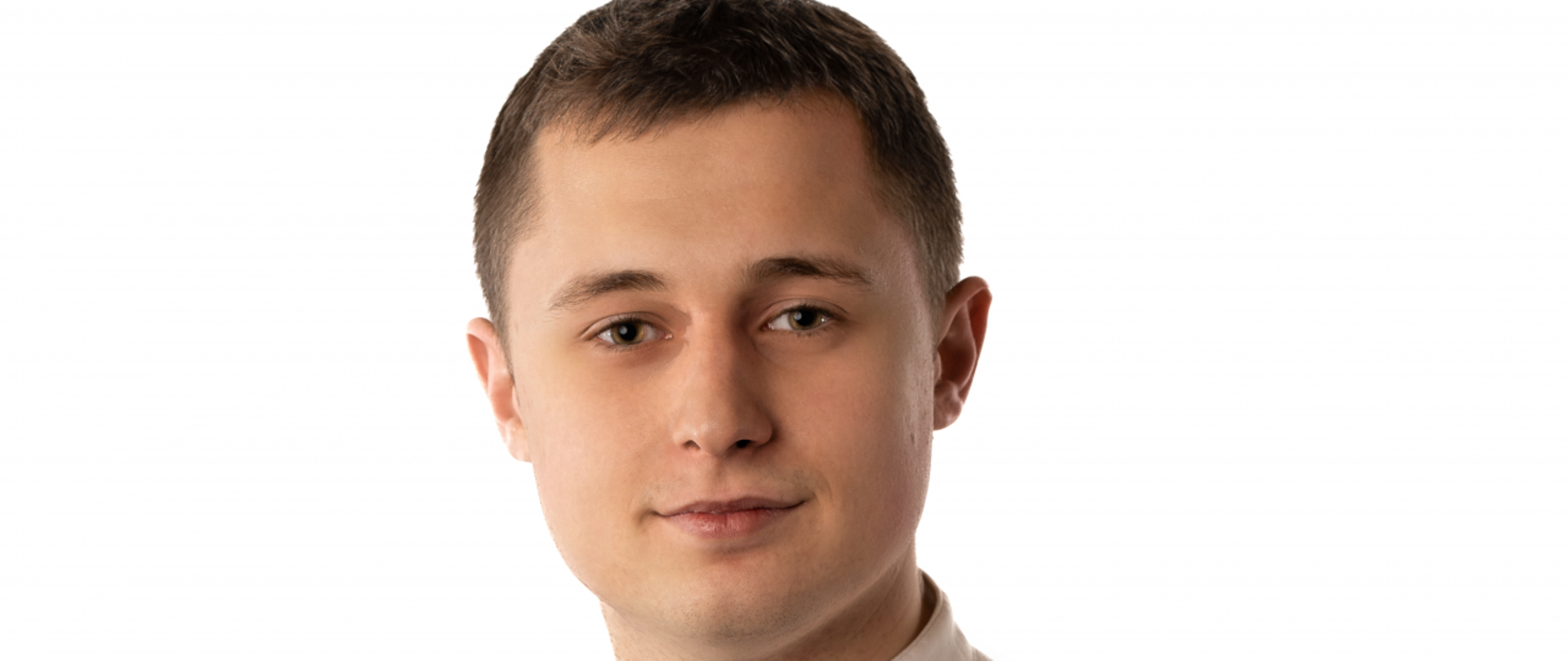 Młody mężczyzna o ciemnych, krótko ściętych włosach, łagodna twarz, ubrany w biała koszule ze stójką z ciemnymi guzikami