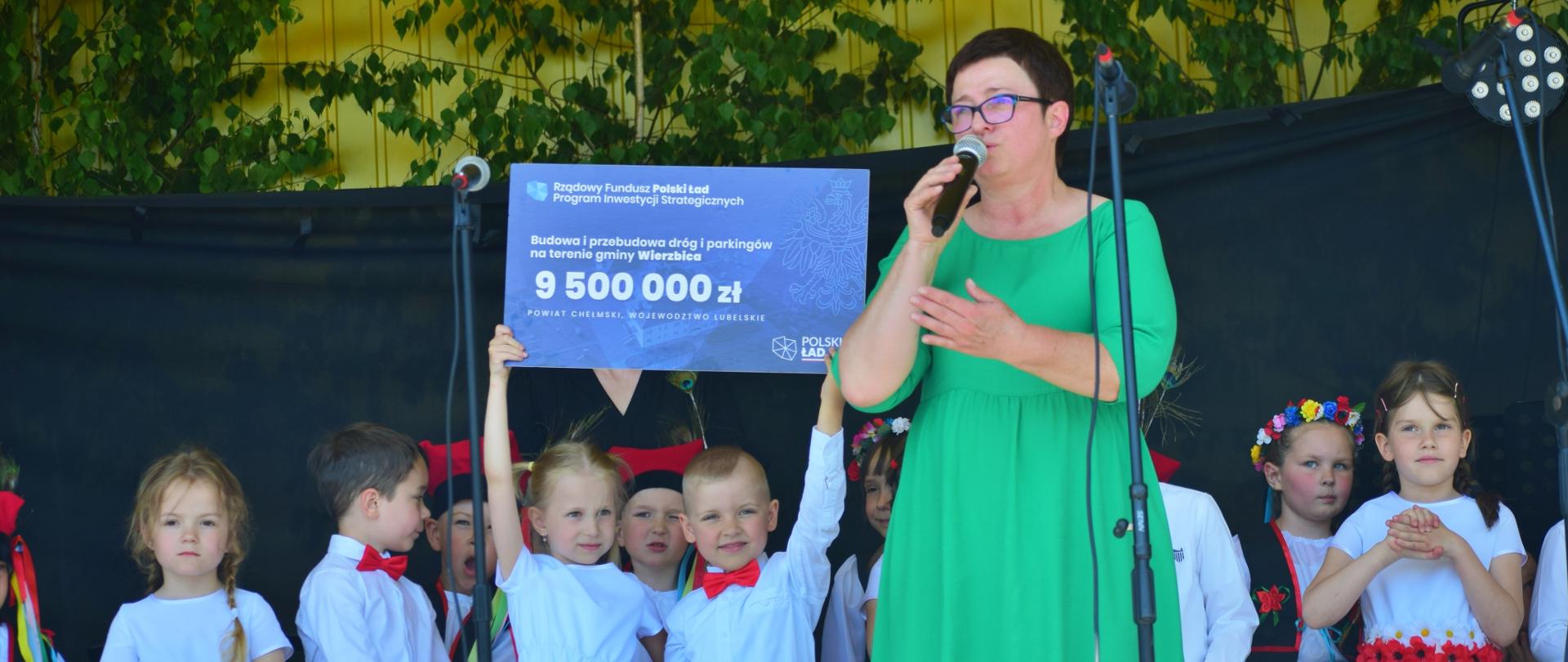 Wręczenie promesy na realizację projektu: Budowa i przebudowa dróg i parkingów na terenie Gminy Wierzbica. Na zdjęciach Wójt Gminy Wierzbica Bożena Deniszczuk, Wiceminister Sprawiedliwości Sebastian Kaleta, w tle dzieci z Gminnego Przedszkola w Wierzbicy