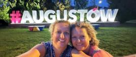Uczestniczki wycieczki pozują przed napisem Augustów