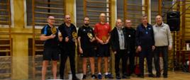 Dekoracja zawodników - siedmiu dorosłych uczestników turnieju stoi z pucharami, obok Organizator - Pan Janusz Ludwiczak