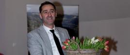 Mężczyzna elegancko ubrany z koszem tulipanów w ręku
