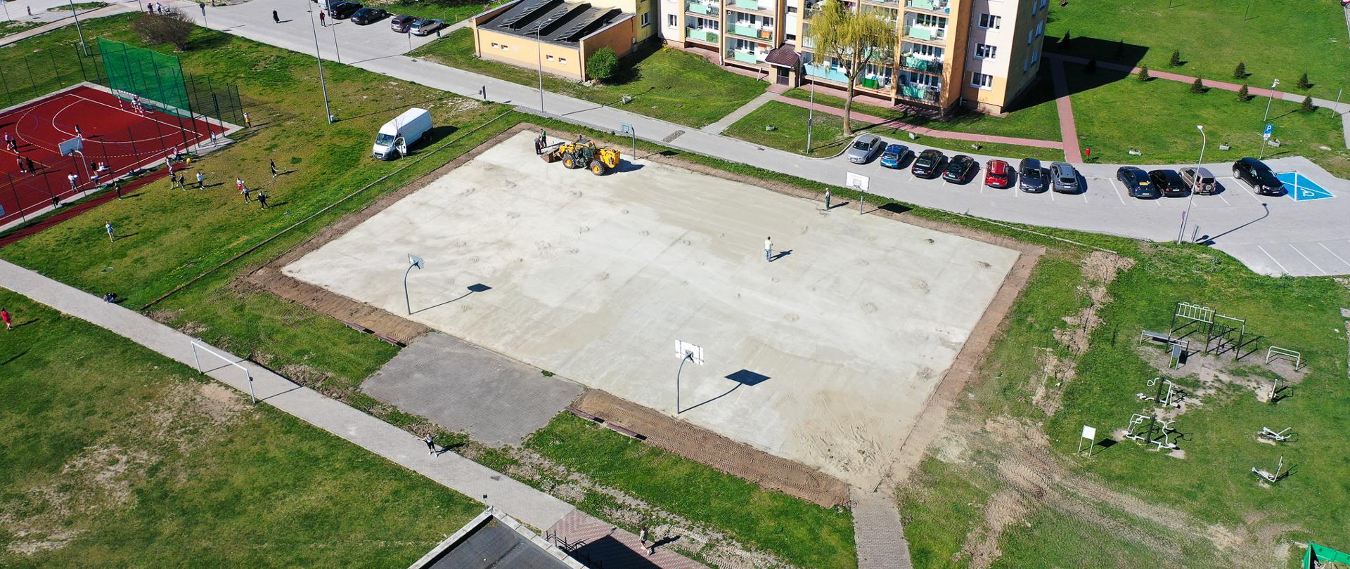 Zdjęcie przedstawia widok z drona na betonowe boisko (plac budowy)