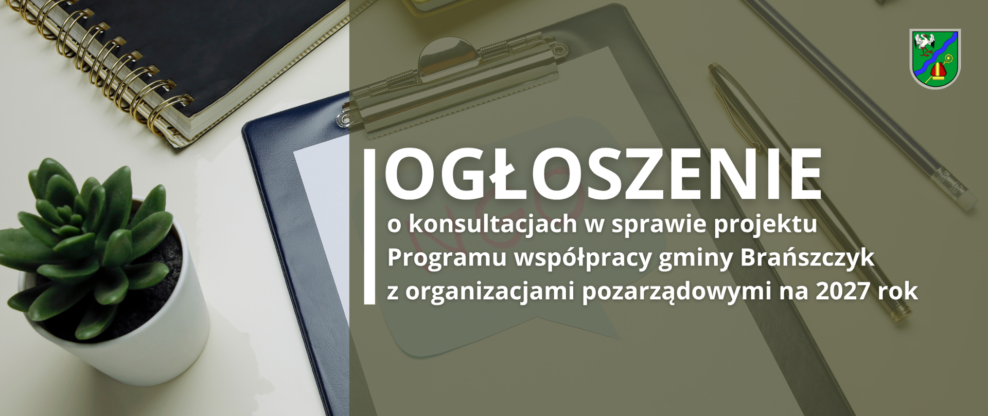Grafika informacyjna na jasnym tle przedstawiającym biurko, na którym znajdują się czarna suknia/podkładka z klipsem, kołonotatnik, mała roślina doniczkowa oraz długopis. W prawym górnym rogu widnieje herb gminy Brańszczyk. W centralnej części umieszczono napis: „OGŁOSZENIE o konsultacjach w sprawie projektu Programu współpracy gminy Brańszczyk z organizacjami pozarządowymi na 2027 rok”. W tle pod napisem widoczny jest również półprzezroczysty napis „NGO” wpisany w dymek dialogowy.