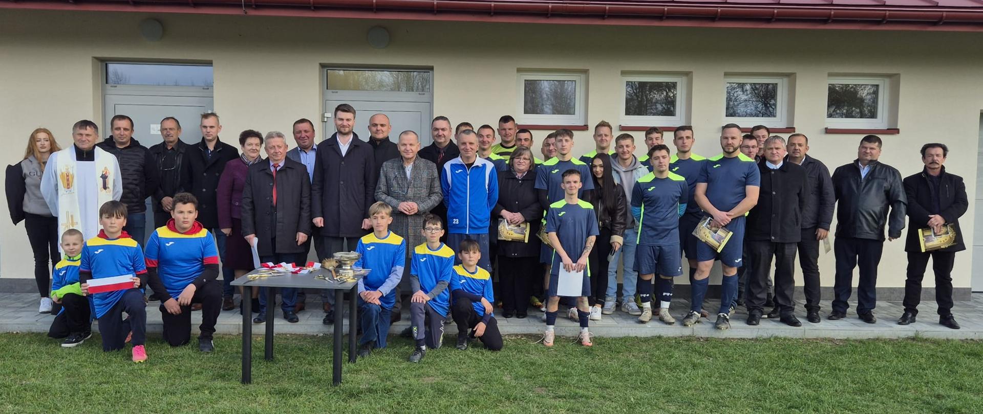 Wspólne zdjęcie po uroczystym otwarciu i poświęceniu nowego budynku szatni sportowej w Ujściu Jezuickim.