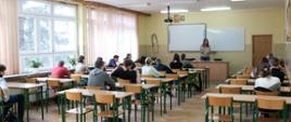Prowadząca cześć teoretyczną tłumaczy uczniom jak wypełnić formularz testowy