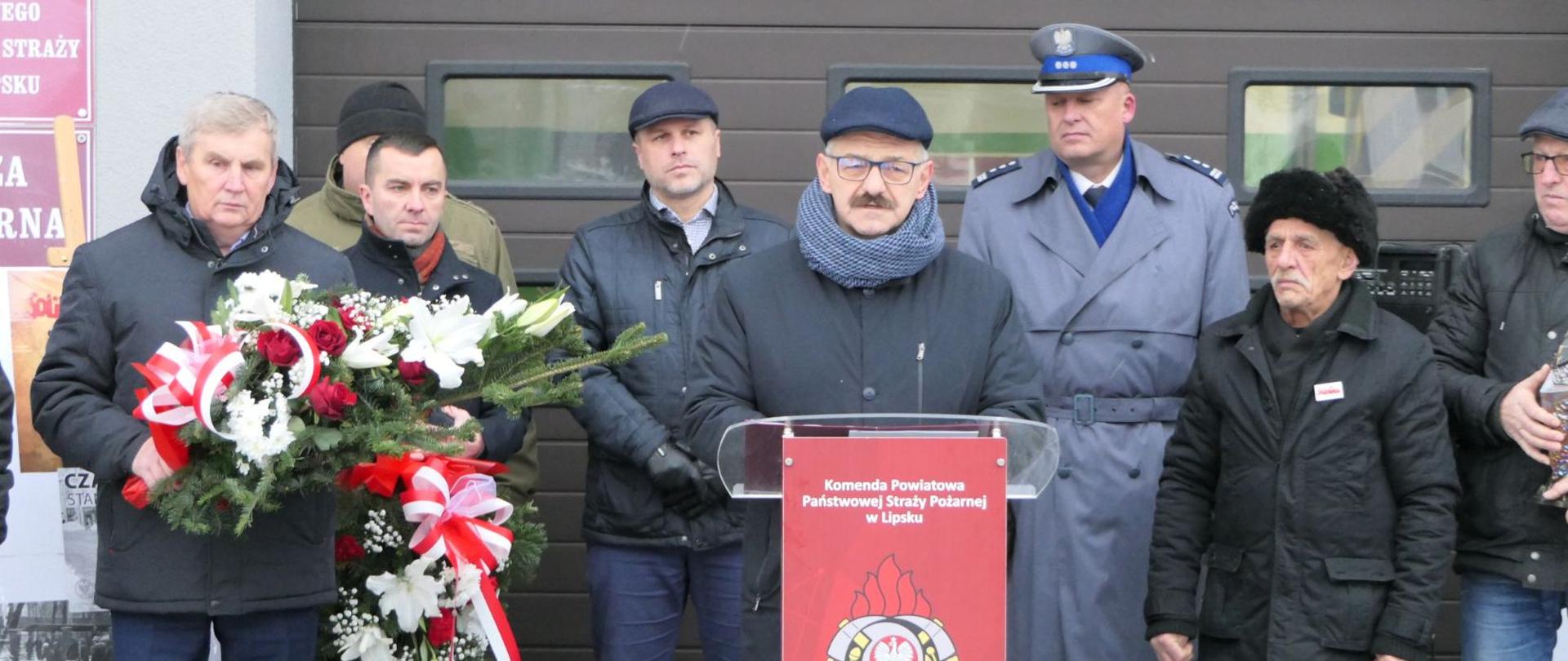 Starosta Lipski przemawia do uczestników uroczystości. Za nim stoją przedstawiciele jednostek powiatu lipskiego.