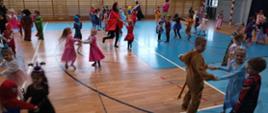 Dzieci w kolorowych, bajkowych przebraniach tańczą na sali gimnastycznej
