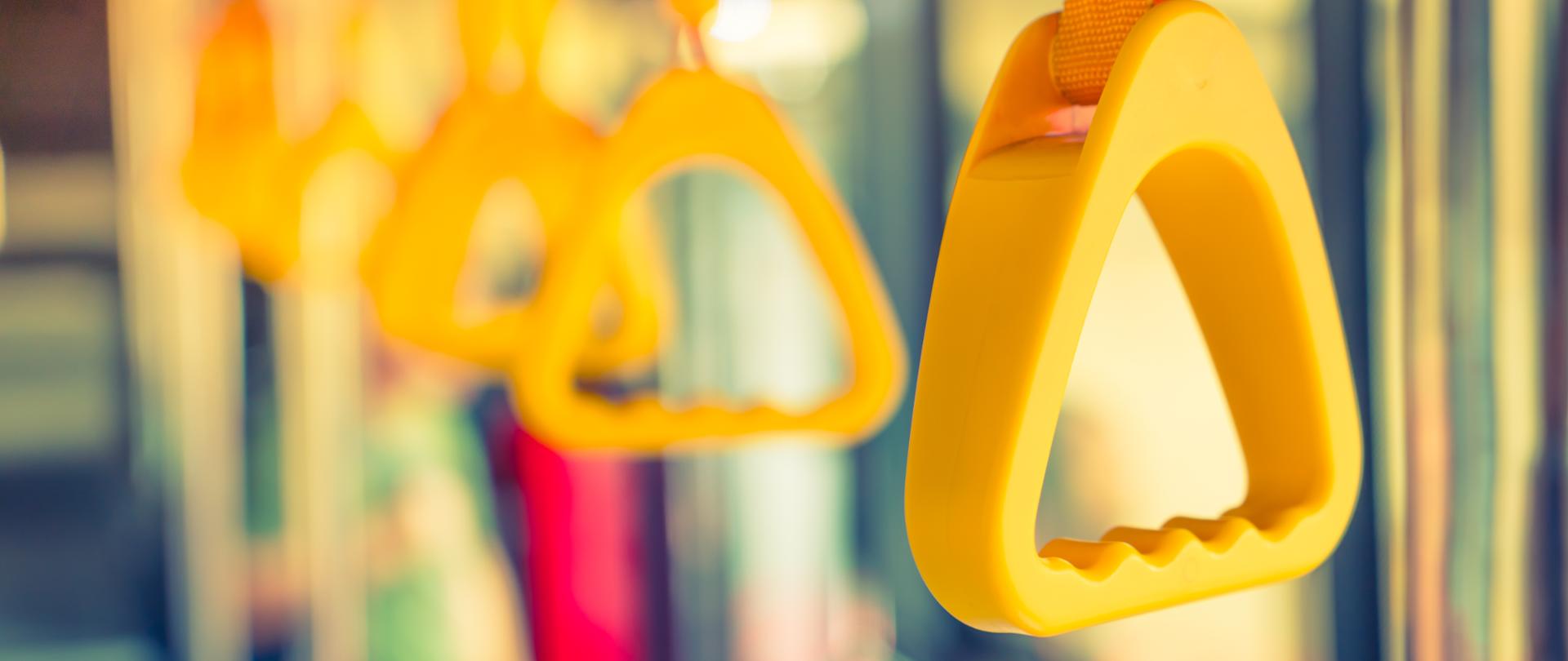 Żółte uchwyty zwisające z poręczy w autobusie