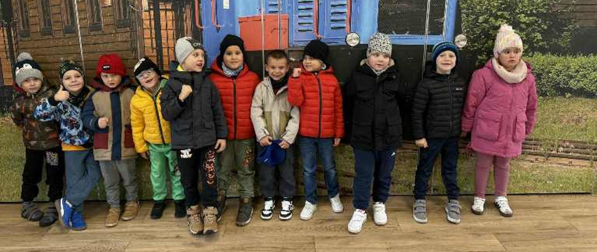 Pozujemy do zdjęcia przy tapecie kolejki wąskotorowej w Ośrodku Edukacji Leśnej Stacja