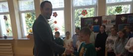 Przedstawiciel firmy PGW Wody Polskie gratuluje laureatowi konkursu, z tyłu stoją pozostali uczestnicy