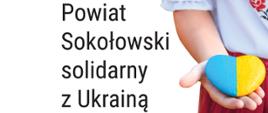 Na białym tle widoczny po lewej tytułowy napis. Po prawej stronie fragment dziewczynki w biało - czerwonym stroju ludowym z wyciągniętą dłonią, na której położone jest kamienne serce w kolorze żółto - niebieskim tj. niebiesko - żółtym.