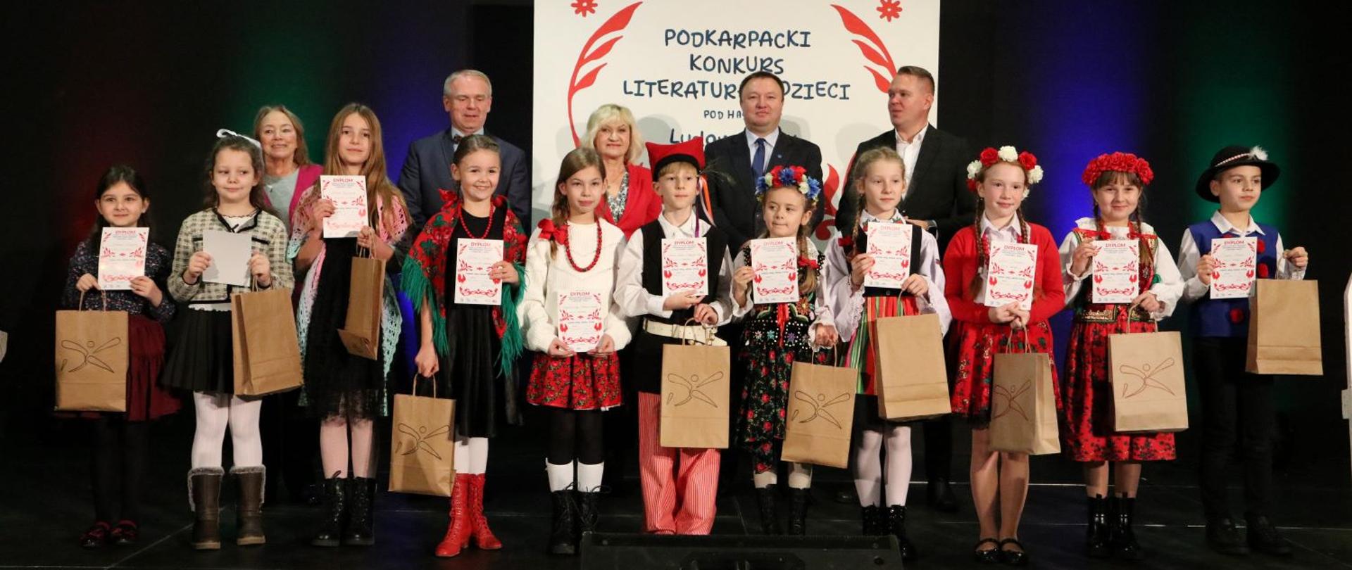 Laureaci konkursu stoją na scenie z dyplomami i nagrodami.