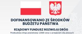 Na szaro- białym tle z flagą i godłem Polski tablica informacyjna- inwestycja dofinansowana ze środków budżetu- Rządowy Fundusz Rozwoju Dróg: Przebudowa drogi powiatowej 1266K wraz z przejściem dla pieszych i chodnikiem w miejscowości Koniusza. 