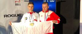 Odznaczony medalami Jakub Bońkowski (po lewej) wraz z trenerem Cezarym Pykałą (po prawej) pozują z biało czerwoną flagą Polski. Zawodnik i trener trzymają biało czerwoną flagę przed sobą.