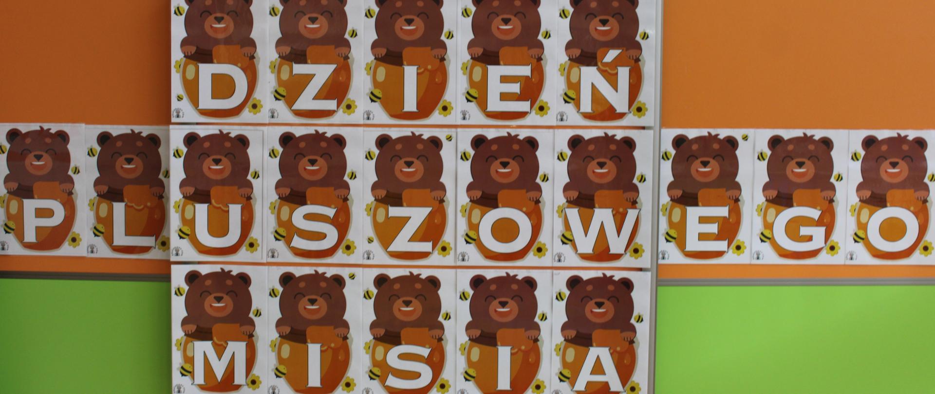 Zdjęcie przedstawia napis : Dzień pluszowego Misia. Napis jest biały, z brązowymi misiami i zółtymi miodami.