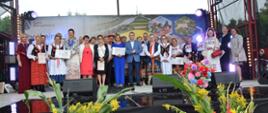 zdjęcie przedstawia kilkadziesiąt osób kobiet i mężczyzn w wieku od 30 do 75 lat stojących na scenie i pozujących do zdjęcia