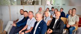 Grupa ludzi wysłuchująca prezentacji