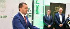 Zdjęcie przedstawia jedną osobę, która stoi i przemawia przy mównicy