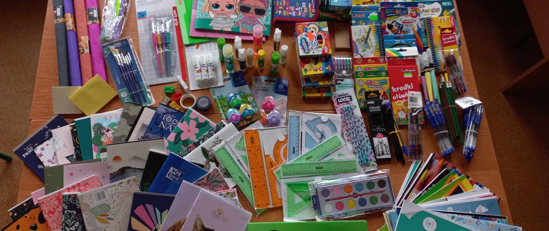Na zdjęciu widoczne artykuły szkolne i papiernicze ułożone na ławce szkolnej.