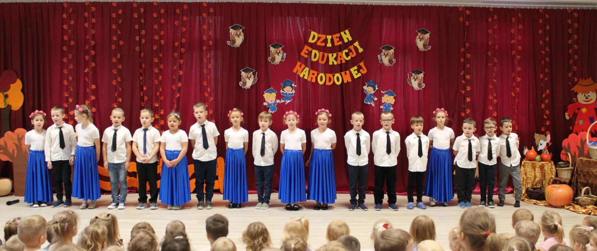 Grupa dzieci na tle napisu DZIEŃ EDUKACJI NARODOWEJ