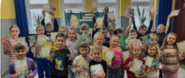 Dzieci trzymają w ręku wykonane przez siebie kartki wielkanocne, stoją na korytarzu szkolnym