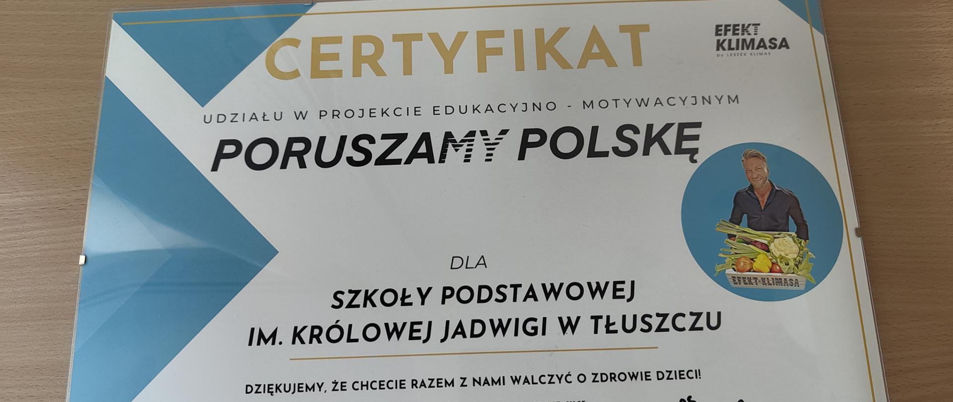 Obrazek mężczyzny trzymającego skrzynkę z warzywami i napisem efekt Klimasa. Certyfikat udziału w projekcie edukacyjno-motywacyjnym Poruszamy Polskę dla Szkoły Podstawowej im. Królowej Jadwigi w Tłuszczu. Dziękujemy, że chcecie razem z nami walczyć o zdrowie dzieci.