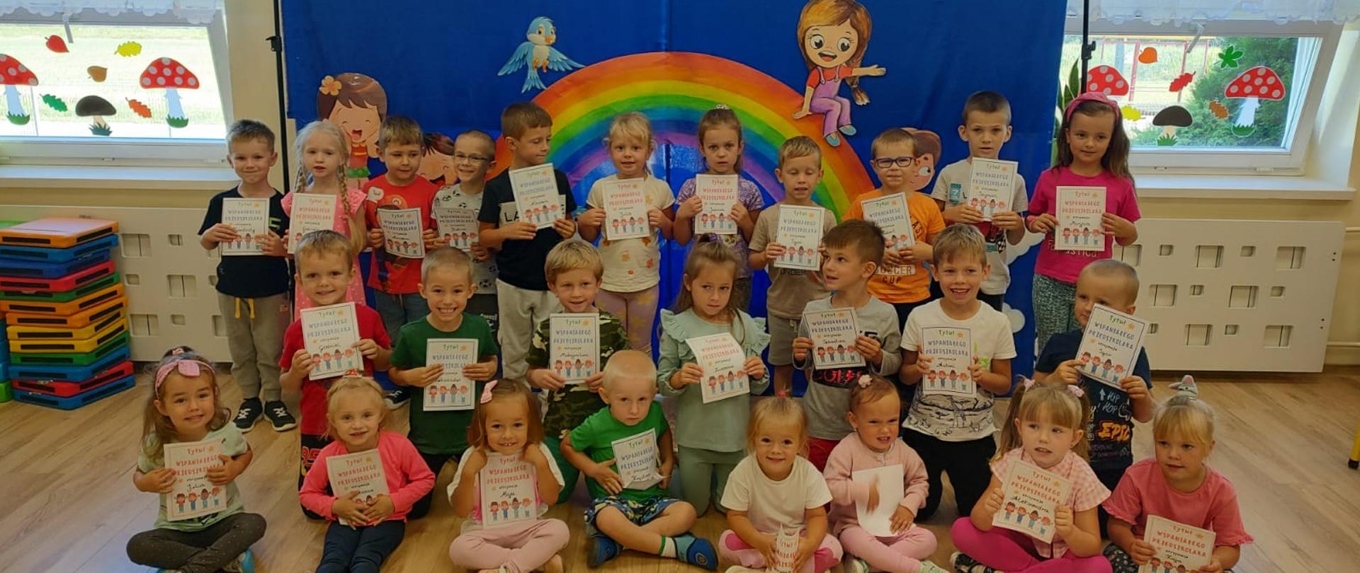 Uśmiechnięte dzieci z przedszkola trzymają w rękach dyplomy