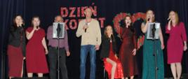 Zdjęcie przedstawia 6 pań i dwóch panów śpiewających podczas występu na dzień kobiet w sali widowiskowej w Ośrodku Kultury.