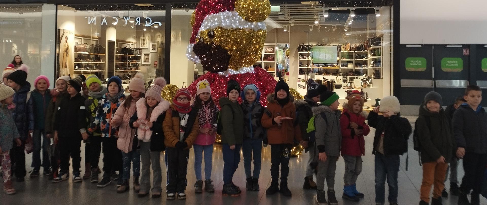 Uczniowie klas I-III w galerii handlowej na tle świątecznych dekoracji