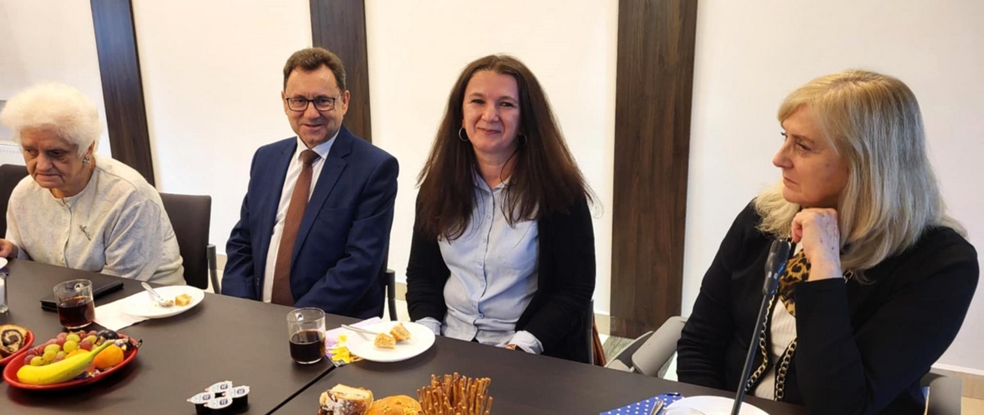 Fotografia wykonana podczas spotkania z okazji Międzynarodowego Dnia Białej Laski. Uczestnicy spotkania siedzą przy poczęstunku m. in. starosta oraz dyrektor PCPR w Sokołowie Podlaskim.