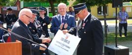 Burmistrz Miasta i Gminy Budzyń przekazujący prezent prezesowi OSP
