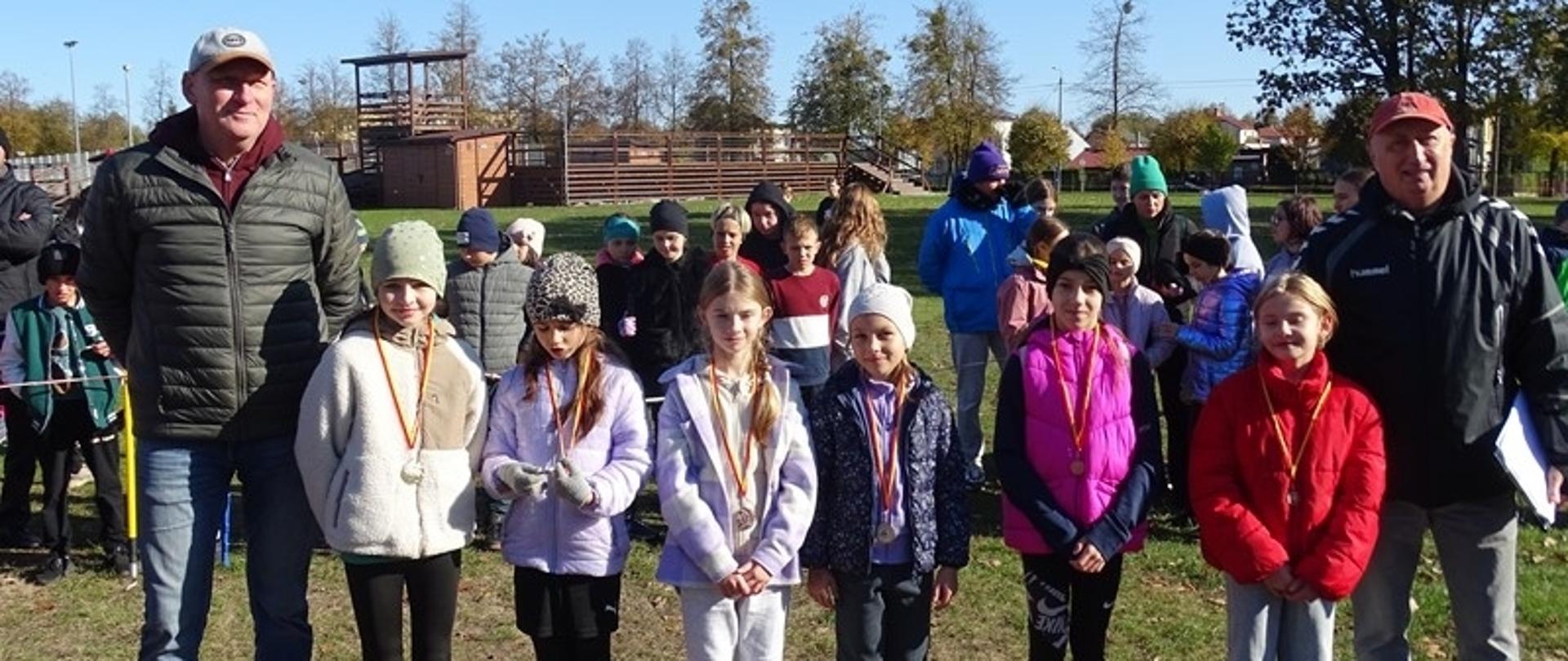 Dekoracje zawodników - młodzi sportowcy pozują do zdjęcia z medalami, przedstawicielem Organizatora i opiekunem