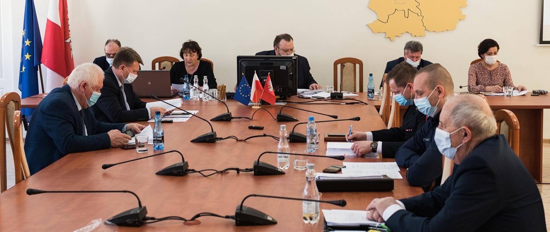 Na zdjęciu siedzący przy stole w maseczkach ochronnych radni powiatowi. Przy stole pod ścianą od lewej siedzą wicestarosta Ryszard Domański, starosta Elżbieta Sadowska, przewodniczący Rady Powiatu Jacek Odziemczyk, wiceprzewodniczący Rady Powiatu Andrzej Kietliński, oraz wiceprzewodnicząca Jolanta Ciołkowska. Na stole widać flagi biało - czerwoną oraz unijną granatową z żółtymi gwiazdami ułożonymi w okręgu. Na ścianie żółty model ze styroduru przedstawiający mapę powiatu oraz duży napis Powiat Sokołowski.
