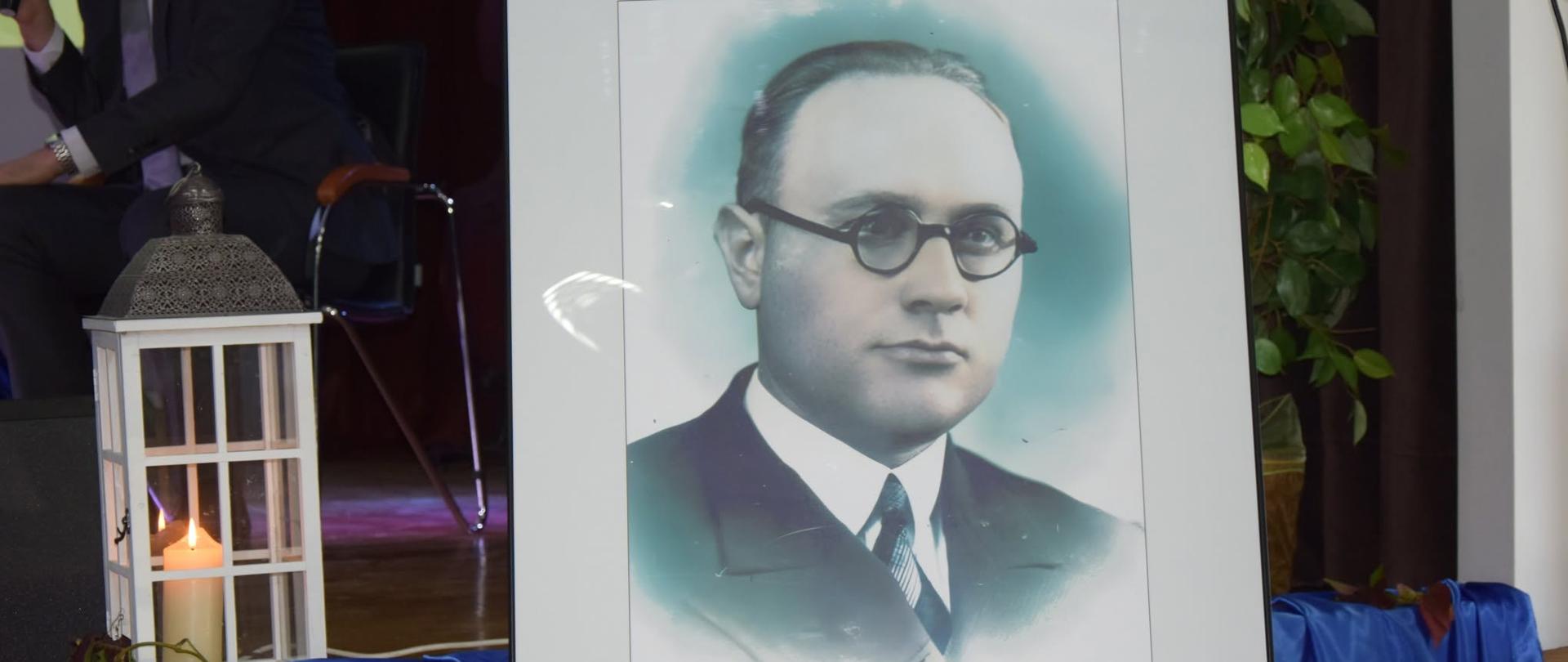 Oprawiony w ramę portret Stanisława Miłkowskiego z podpisem oraz datami urodzin i śmierci (1905–1945), ustawiony obok lampionu ze świecą.