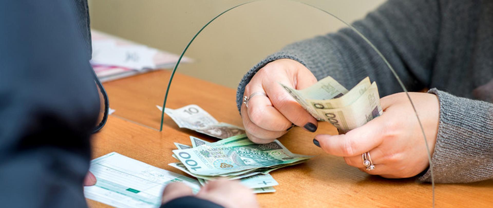zdjęcie przedstawia dłonie kobiety liczące pieniądze 