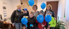 Zdjęcie grupowe, na którym widzimy dzieci z Zespołu Szkół Specjalnych im. Jana Pawła II w Sokołowie Podlaskim oraz starostę Elżbietę Sadowską. Czwórka dzieci na zdjęciu trzyma w rączkach niebieskie balony z logo szkoły i napisem Światowy Dzień Świadomości Autyzmu. Dodatkowo na zdjęciu widzimy dyrektora szkoły oraz jedną z nauczycielek. W tle gabinet starosty sokołowskiego.