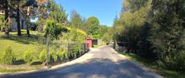 Nowopowstała droga asfaltowa w miejscowości Sieniawa. W tle zielone drzewa i niebieskie niebo.
