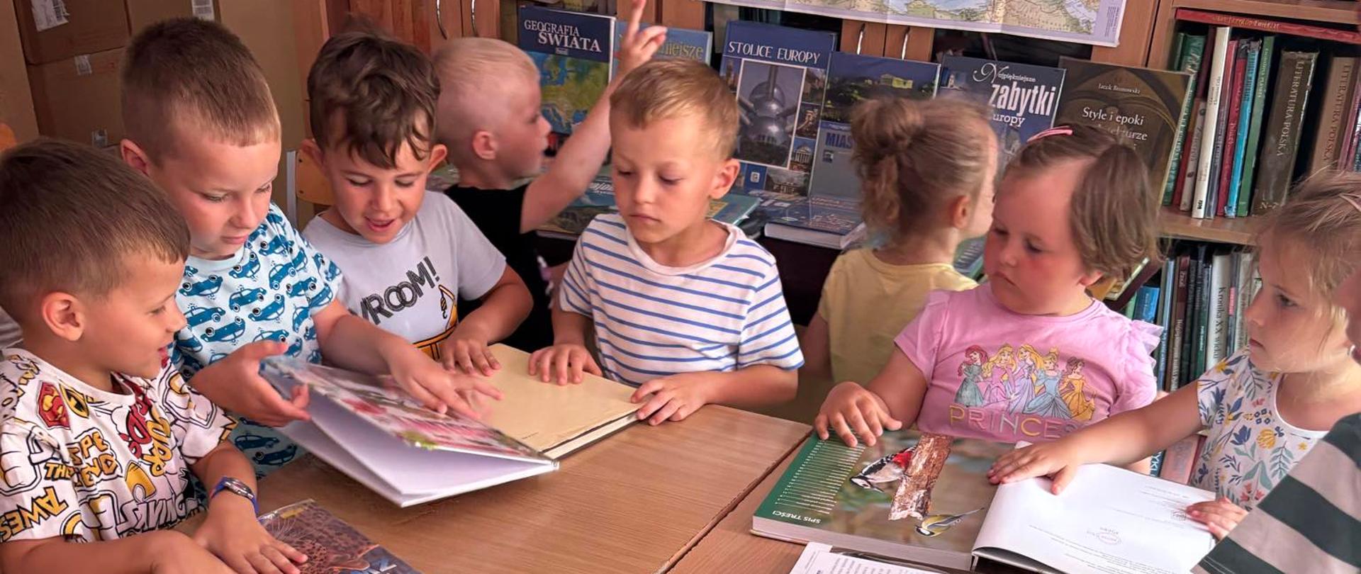 Dzieci oglądają książki podczas wizyty w bibliotece szkolnej