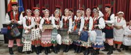 Grupa ludzi w ludowych strojach trzyma w rękach paczki z darami