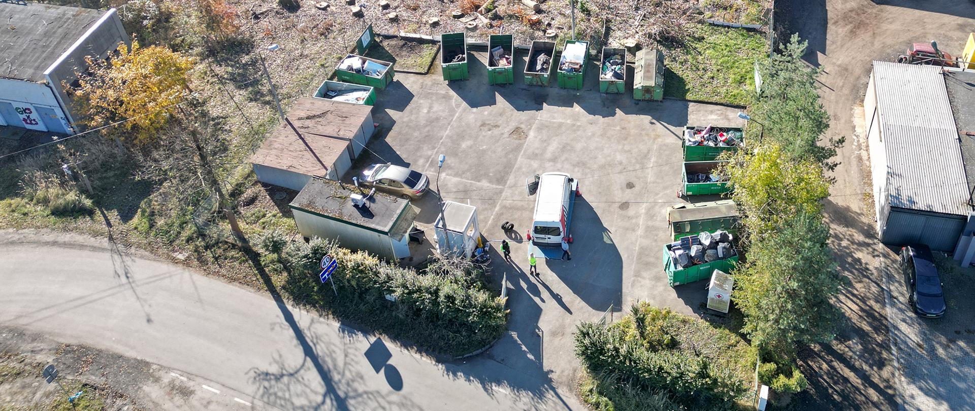 Asfaltowy plac na którym znajdują się duże pojemniki na odpady.