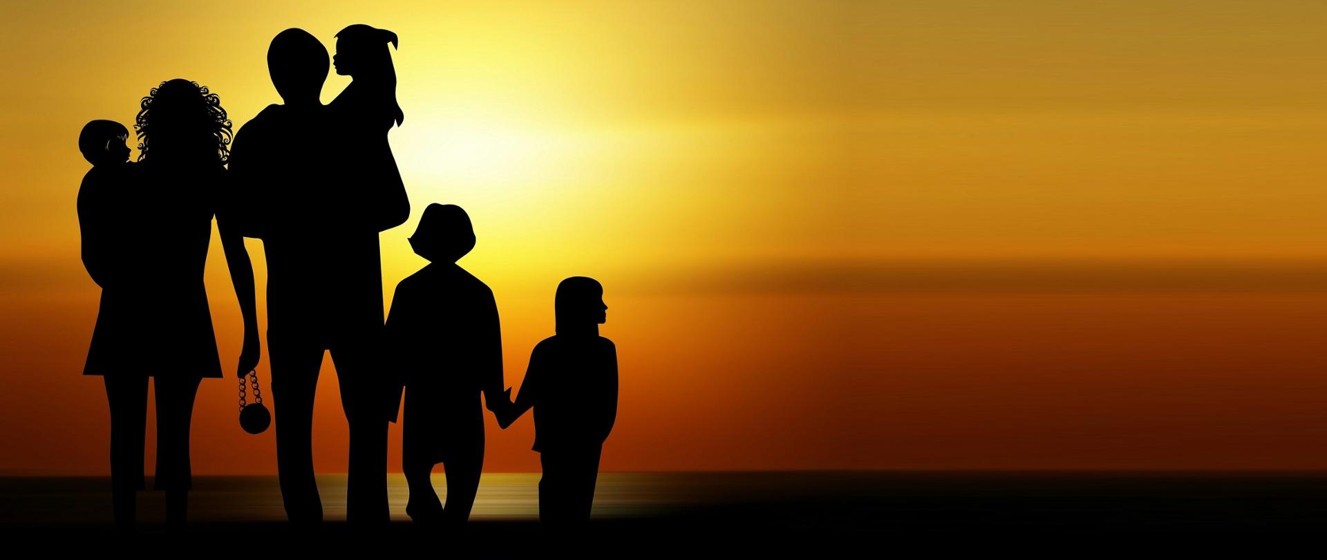 Duża rodzina - cienie ludzi. Dwóch dorosłych i troje dzieci na tle zachodzącego słońca