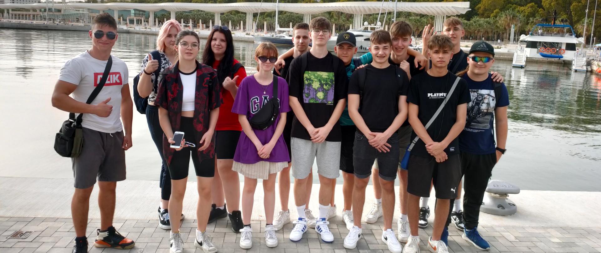 Grupa uczniów pozuje do zdjęcia na tle wybrzeża w Hiszpanii