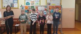 Pani dyrektor ogłasza wyniki konkursu. Laureaci ustawieni na tle tablicy prezentującej wykonane prace.