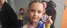 Antosia trzyma w ręku puchar i medal z jedynką za sukcesy w tańcu baletowym
