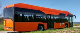 Zdjęcia przedstawiające elektryczny autobus szkolny służący do przewozu dzieci uczących się w szkole podstawowej w Krasnopolu. Autobus w kolorze pomarańczowym. Na masce autobusu (z prawej strony) znajdują się naklejki informujące o tym, że autobus jest dostoswany do przewozu osób niepełnosprawnych oraz wózków dziecięcych. Na masce autobusu (z jego prawej strony) umieszczono tablicę „uwaga dzieci”. Na prawym boku autobusu umieszczono herb gminy Krasnopol oraz informacje o tym, że zakup autobusu został sfinansowany ze Środków narodowego Funduszu Ochrony Środowiska i Gospodarki Wodnej.