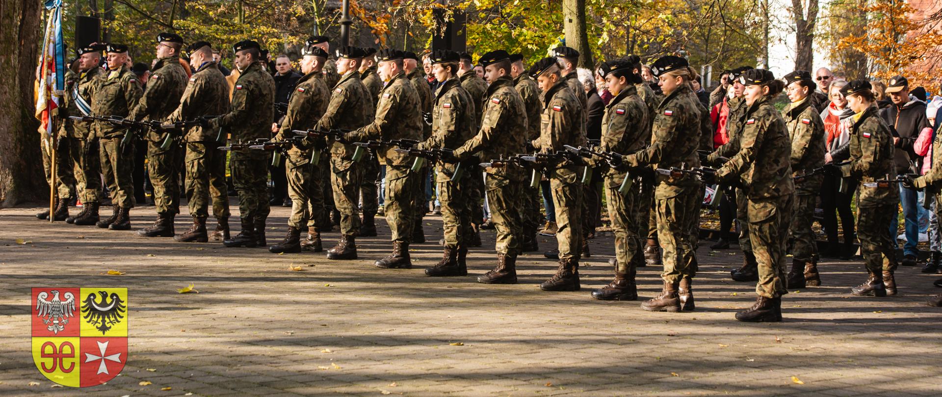 grupa żołnierzy i żołnierek na zewnątrz, z bronia w rękach