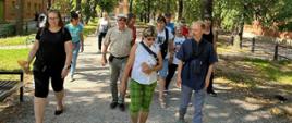 Uczestnicy wycieczki spacerują parkową aleją
