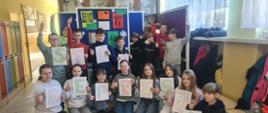 Uczniowie klasy 5 stoją na korytarzu szkolnym w dwóch rzędach, każdy trzyma w ręku kartkę z jedną dużą literką, litery tworzą napis "Stop depresji"