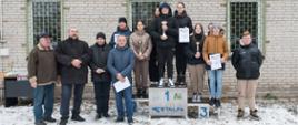 Na zdjęciu organizatorzy turnieju oraz zwycięzcy szkoły podstawowej stojący na podium .