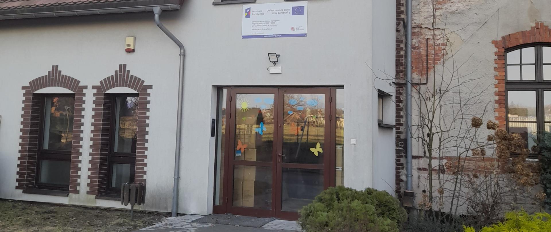 Biały budynek ze spadzistym dachem i dużymi oknami
